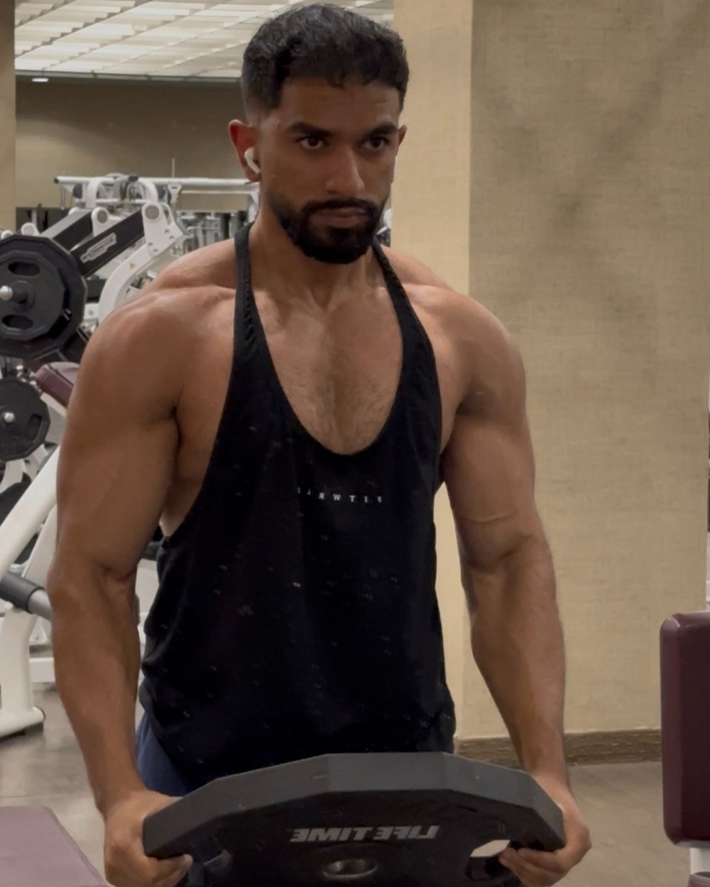 Ayyan holding a weight plate in the gym